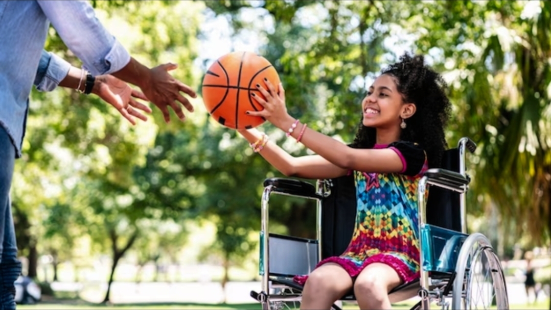 Young girl in wheelchair playing with a basketball