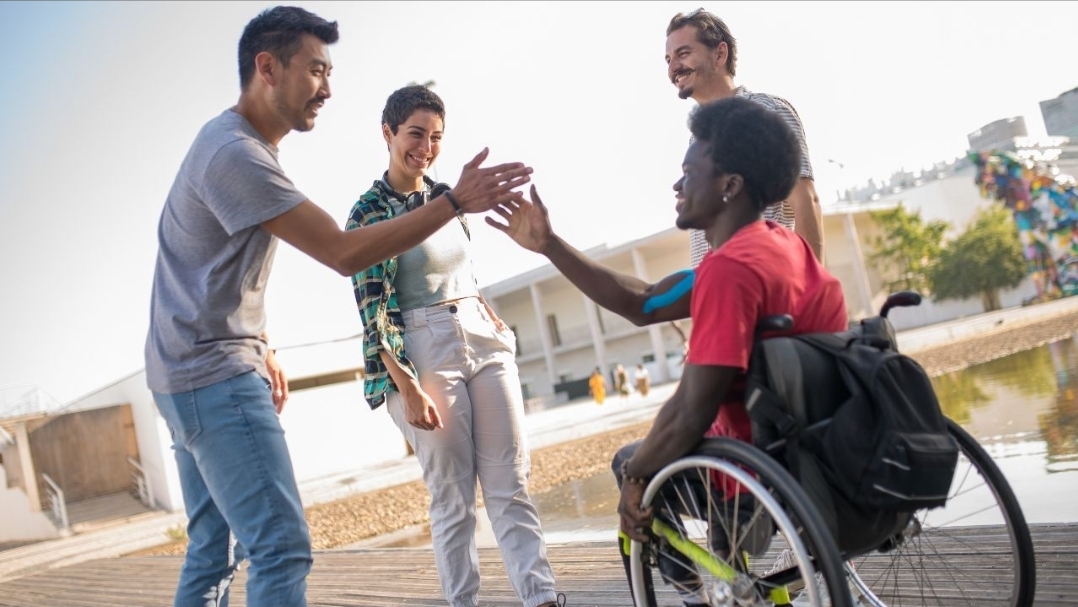 People interacting inclusively with a person in a wheelchair
